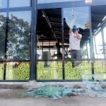 El propietario de uno de los locales afectados retira una cristalera tras los incidentes registrados la pasada noche