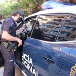 Un agente junto a un coche patrulla