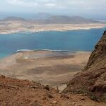 Salinas del Río en la base del escarpe de Famara (Lanzarote) y al otro lado la isla de La Graciosa donde se ha descubierto el depósito de oleaje de época Romana.
