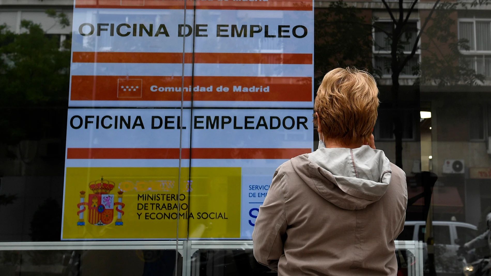 Una mujer observa un anuncio de una Oficina del Servicio Público de Empleo Estatal (SEPE