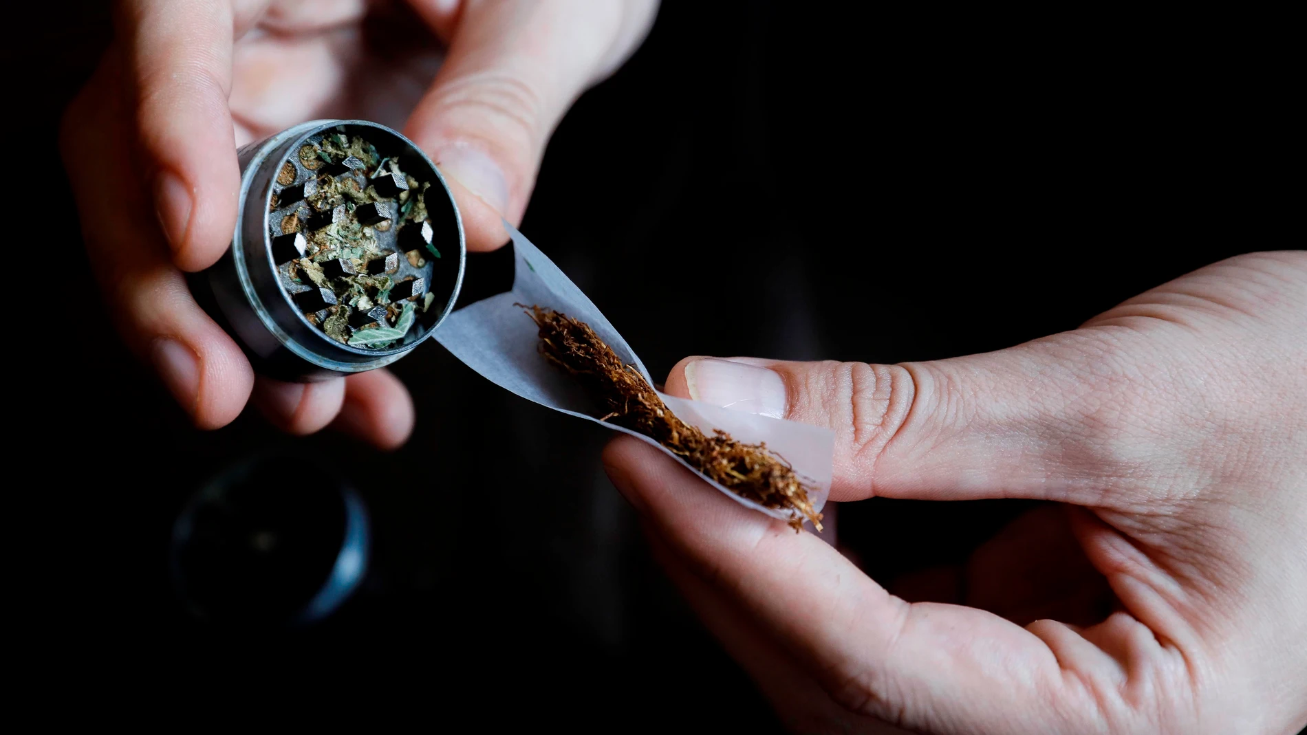 En la imagen, una persona se lía un cigarro con marihuana