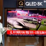 Una mujer delante de una televisión con la noticia del lanzamiento de un misil de Corea del Norte