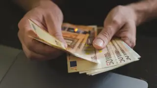 Una persona cuenta billetes de 50 euros Una persona cuenta billetes de 50 euros