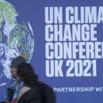 FILE - Attendees walk past a banner at the venue of the COP climate conference in Glasgow, Scotland, on Oct. 29, 2021. On Friday, Nov. 5, The Associated Press reported on stories circulating online incorrectly claiming a photo showed jets used by attendees to get to the conference. In fact, the photo was taken during the 2013 Super Bowl in New Orleans. (AP Photo/Alastair Grant, File)