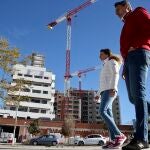 Dos jóvenes pasan por delante de un edificio de viviendas en construcción