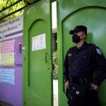 -FOTODELDÍA- AME9621. SAN SALVADOR (EL SALVADOR), 22/11/2021.- Un agente policial custodia la sede de la organización de mujeres "Mélida Anaya Montes", hoy, en San Salvador (El Salvador). La Fiscalía de El Salvador allanó este lunes la sedes de al menos siete organizaciones no gubernamentales en una supuesta investigación por corrupción, lo que defensores de derechos humanos catalogaron como "persecución política". Esta acción judicial también se da en momentos en que organismos internacionales han advertido del "hostigamiento" a voces críticas en el país centroamericano mediante una ley de agentes extranjeros, comparada con la de Nicaragua. EFE/ Rodrigo Sura