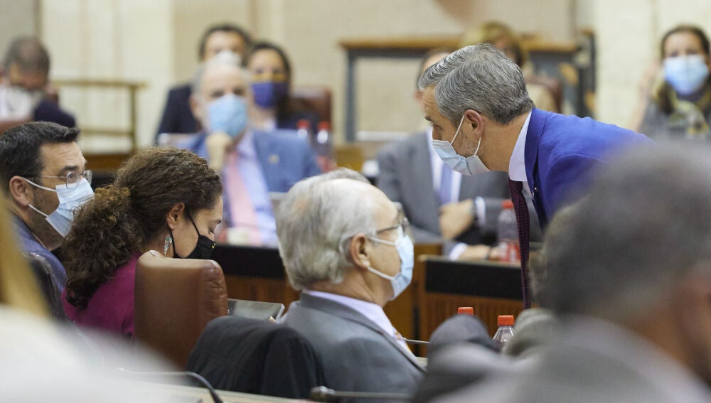 El consejero de Hacienda y Financiación Europea, Juan Bravo, (d) se acerca al escaño de la portavoz del grupo parlamentario Unidas Podemos, Inmaculada Nieto, (i). Joaquín Corchero / Europa Press