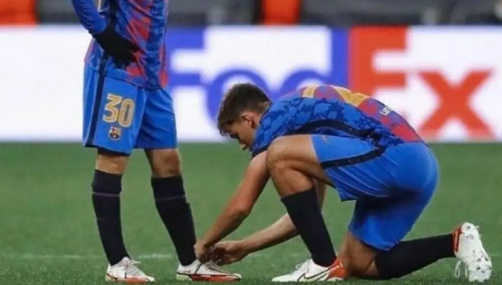 Nico le ata los cordones de una bota a Gavi