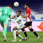 El guardameta belga del Real Madrid, Thibaut Courtois (i), despeja el balón ante su compañero, el brasileño Militao y el delantero del Athletic Club, Raúl García (d), durante el encuentro de LaLiga