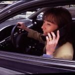 MUJER AL VOLANTE DE UN COCHE HABLANDO POR UN TELEFONO MOVIL