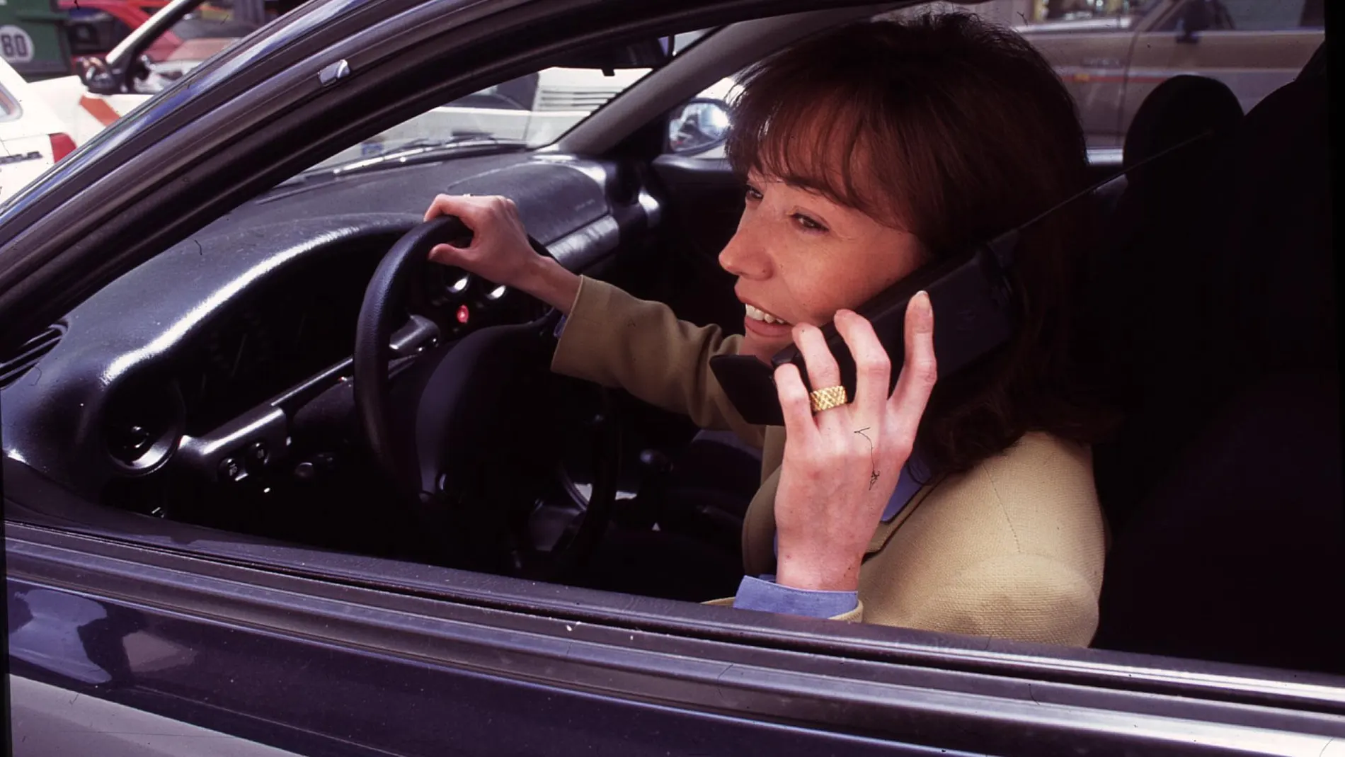 MUJER AL VOLANTE DE UN COCHE HABLANDO POR UN TELEFONO MOVIL