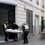Operarios del retén fúnebre sacan el cadáver de mujer de 30 años de edad asesinada presuntamente a manos de un hombre con el que mantenía una relación sentimental.