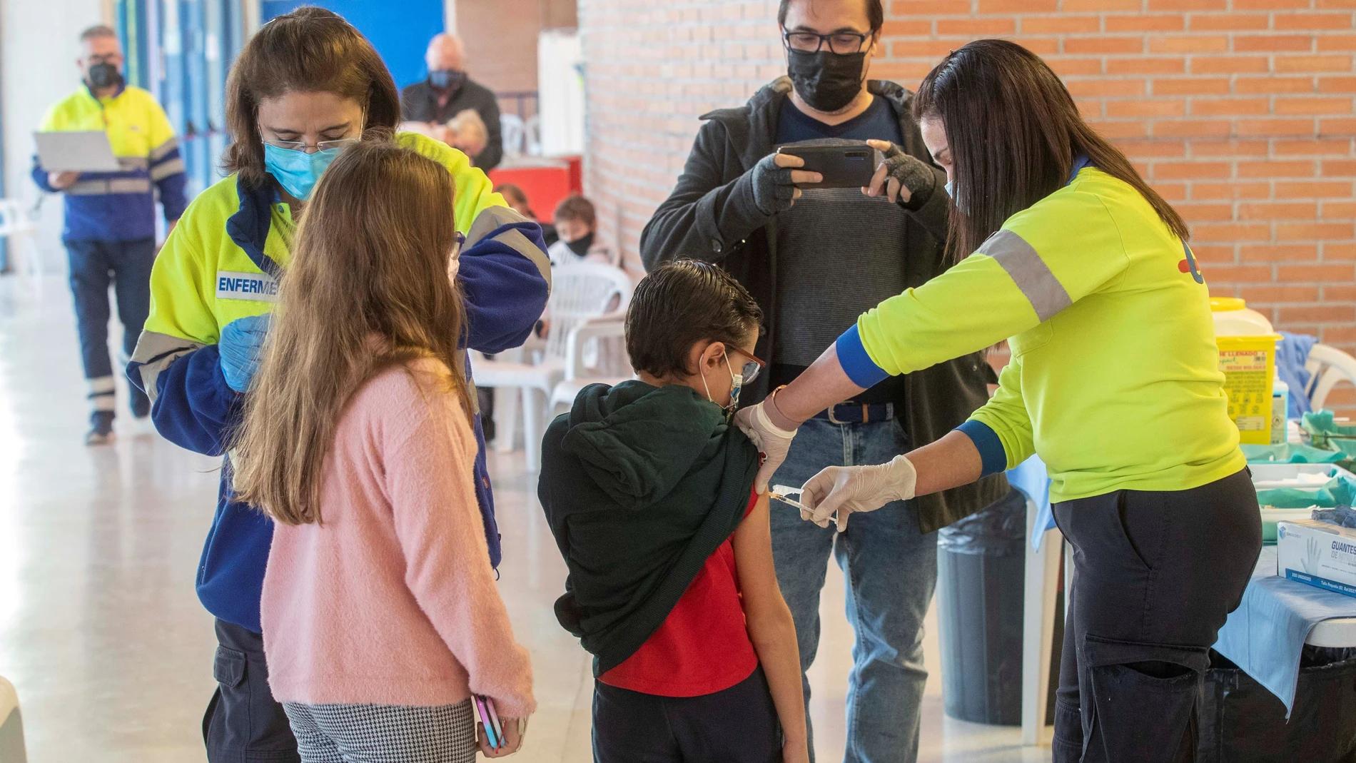 Una enfermera de Servicio Murciano de Salud administra la vacuna de la covid a un niño acompañado, este miércoles en el Palacio de los Deportes de Murcia