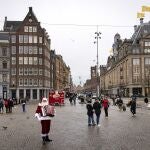Personas pasan por el centro de Ámsterdam, casi vacío por el confinamiento impuesto por el gobierno de los Países Bajos