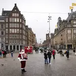 Personas pasan por el centro de Ámsterdam, casi vacío por el confinamiento impuesto por el gobierno de los Países Bajos