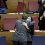 El presidente de la Generalitat, Ximo Puig, abraza a la vicepresidenta del Consell, Mónica Oltra, durante el pleno de Les Corts Valencianes que ha aprobado los Presupuestos de la Generalitat para 2022