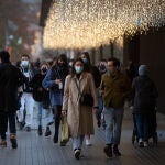 Viandantes caminan con bolsas por una vía de Barcelona,