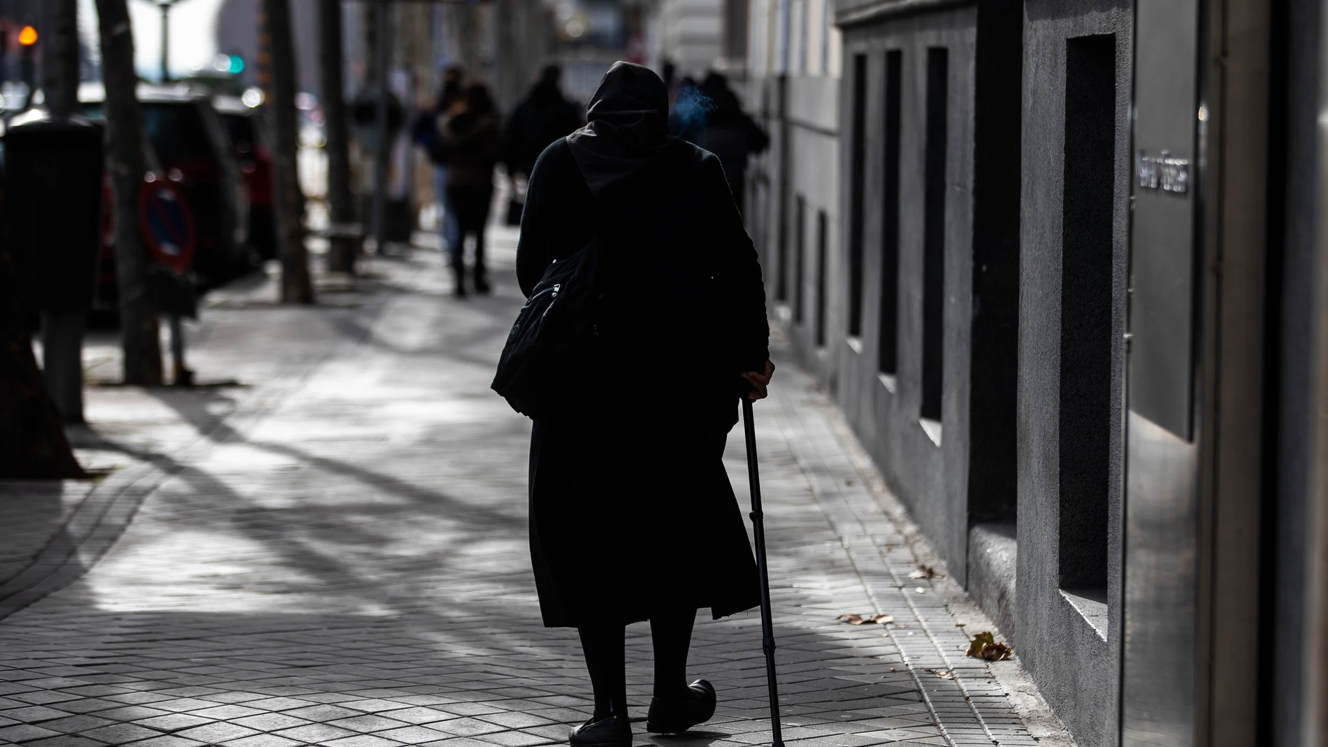 Una mujer de la tercera edad camina por una calle de Madrid