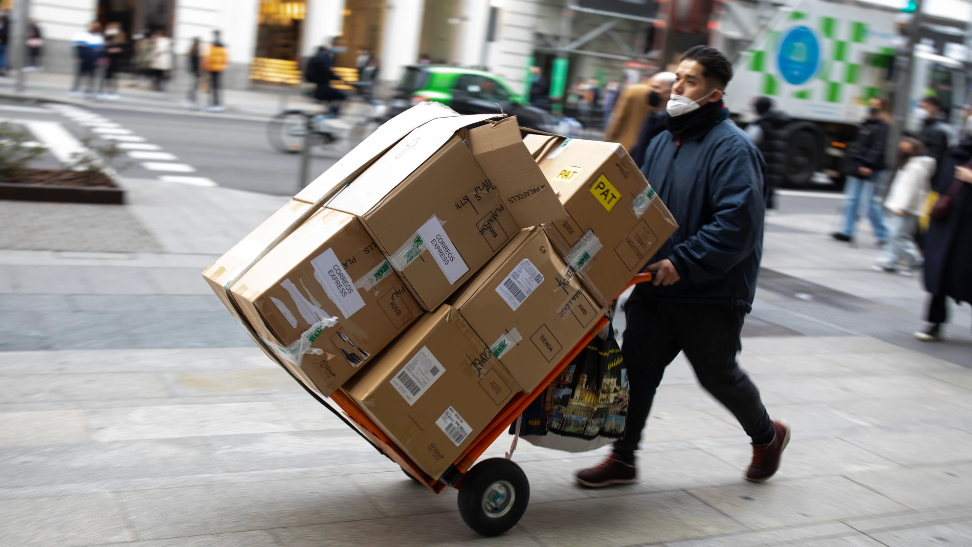 Repartidor de mercancías con un carro lleno de cajas por el centro de Madrid