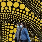 Unas mujeres con mascarillas pasan delante de un centro de recogida de muestras para la detección de casos de coronavirus al lado del Museo de Tel Aviv en Tel Aviv, Israel
