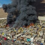 Houses burn during a fire in the low income neighborhood of Laguna Verde, in Iquique, Chile, Monday, Jan. 10, 2022. According to authorities the fire destroyed close to 100 homes of the neighborhood which is populated mostly by migrants. (AP Photo/Ignacio Munoz)