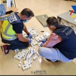 Dos agentes de Policía examinan parte del material que se ha incautado