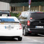 Un taxi pasa junto a un vehículo VTC parado