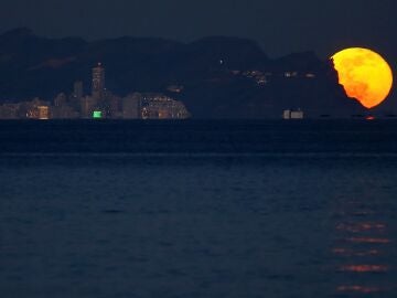 La primera luna llena del 2022 es vista desde la playa de San Juan a su salida por Benidorm.