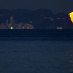 La primera luna llena del 2022 es vista desde la playa de San Juan a su salida por Benidorm.
