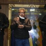 Police escort former police colonel Maximiliano Davila, center, as he was presented to the media at a Bolivian Police Command office, in La Paz, Bolivia, Sunday, Jan. 23, 2022. Authorities announced the capture of Colonel Davila, the former anti-drug director of the Bolivian police, for being tied to a wide drug trafficking ring. (AP Photo/Juan Karita)