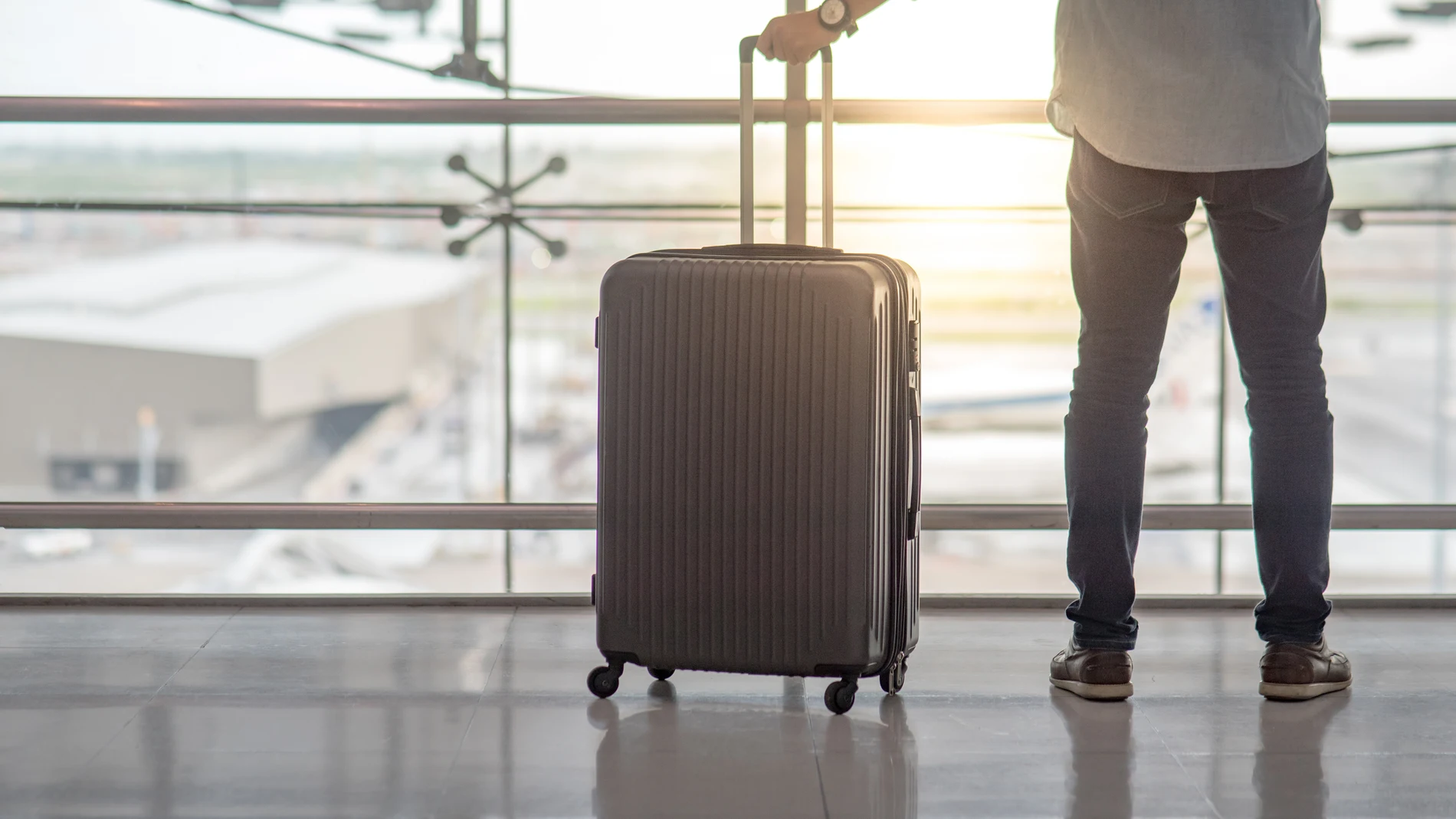 Un hombre lleva una maleta de mano en un aeropuerto