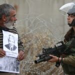 Un manifestante palestino muestra una foto de Nelson Mandela a un soldado israelí en Cisjordania