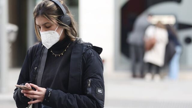 Una mujer camina por la calle con mascarilla