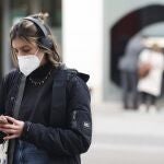 Una mujer camina por la calle con mascarilla