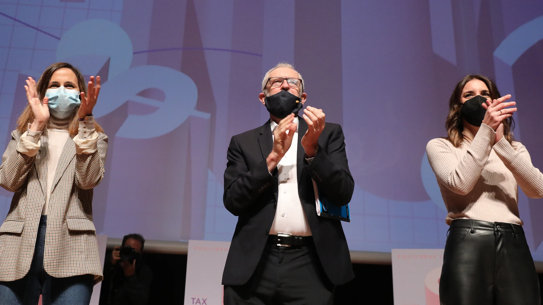 La secretaria general de Podemos y ministra de Derechos Sociales y Agenda 2030, Ione Belarra; el presidente de los técnicos de Hacienda (Gestha), Carlos Cruzado; y la ministra de Igualdad, Irene Montero, aplauden en el acto ‘Tax the Rich. Equilibrar la balanza fiscal