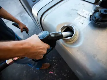 Imagen de un camionero reportando gasóleo a su camión Imagen de un camionero reportando gasóleo a su camión