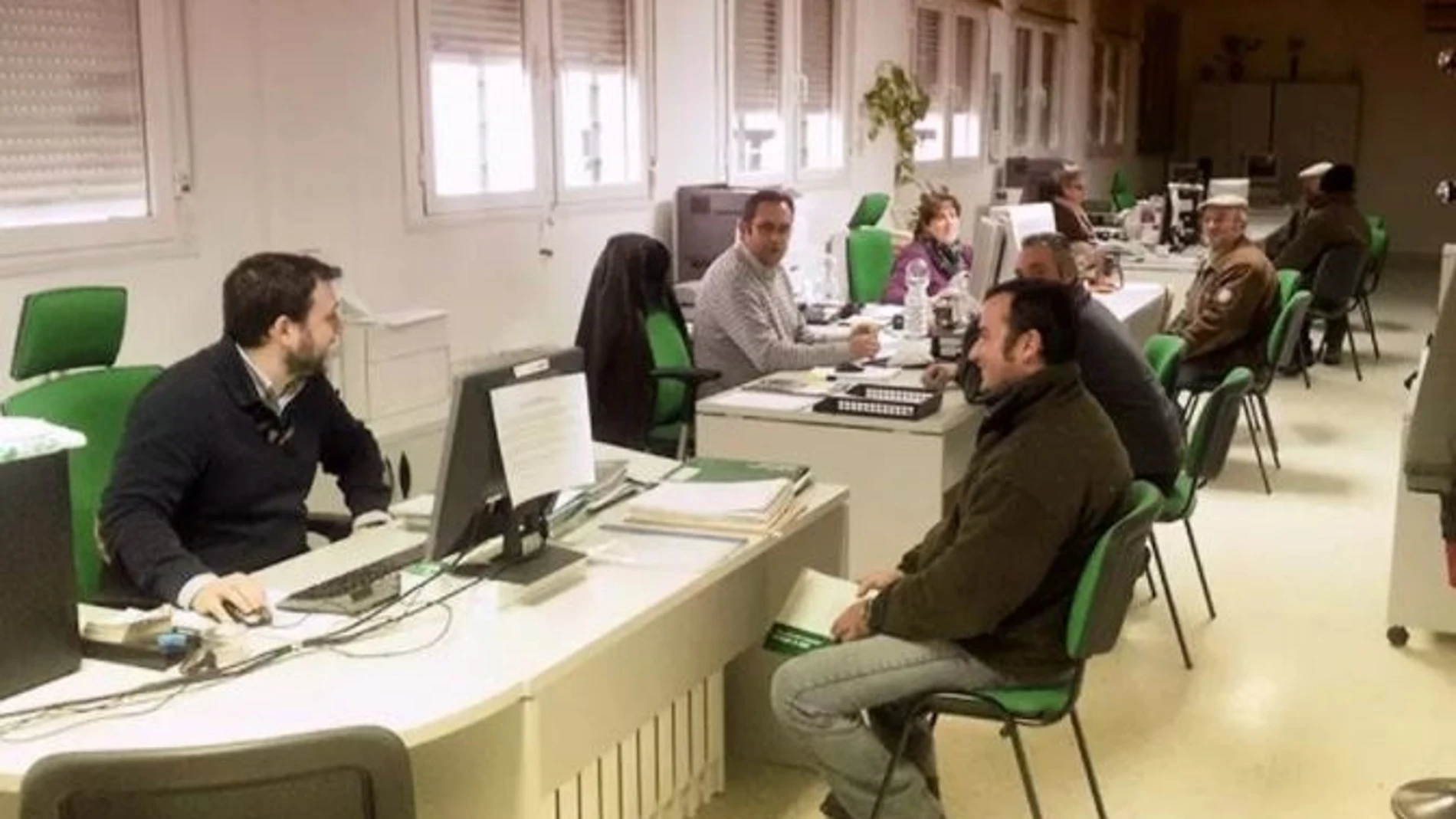 Agricultores atendidos por funcionarios en una oficina comarcal agraria