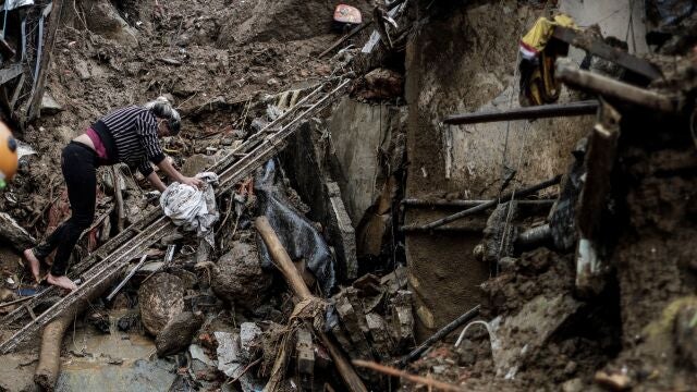 Una mujer intenta caminar sobre los escombros ocasionados tras fuertes lluvias hoy, en Petrópolis (Brasil)