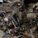 Una mujer intenta caminar sobre los escombros ocasionados tras fuertes lluvias hoy, en Petrópolis (Brasil)