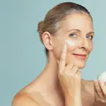 Mujer madura sostiene un tarro de crema hidratante de piel para en antienvejecimiento