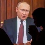 Dos personas observan el discurso televisado del presidente ruso Vladimir Putin en Moscú