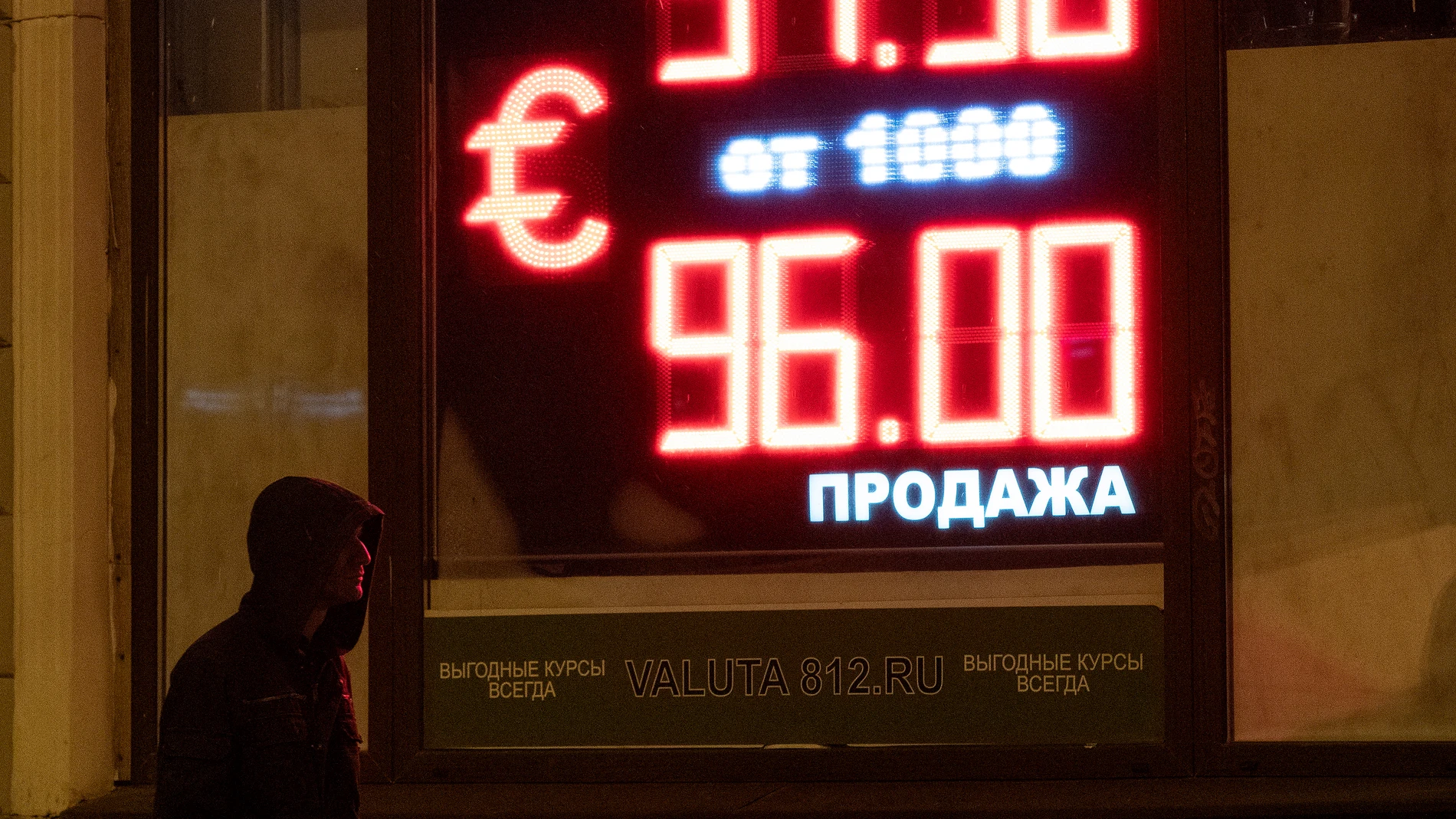 Un hombre camina frente a un panel digital que muestra el tipo de cambio del euro en una oficina de cambio en San Petersburgo, Rusia,