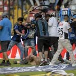 Un aficionado intenta patear la cabeza de otro que está indefenso tirado en el suelo