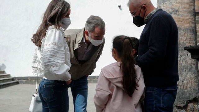 El rey Felipe VI (i) y la reina Letizia (2i) conversan con dos vecinos durante su paseo por la Plaza de España en Santa Cruz de La Palma.