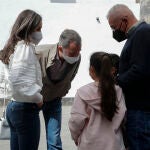 El rey Felipe VI (i) y la reina Letizia (2i) conversan con dos vecinos durante su paseo por la Plaza de España en Santa Cruz de La Palma.