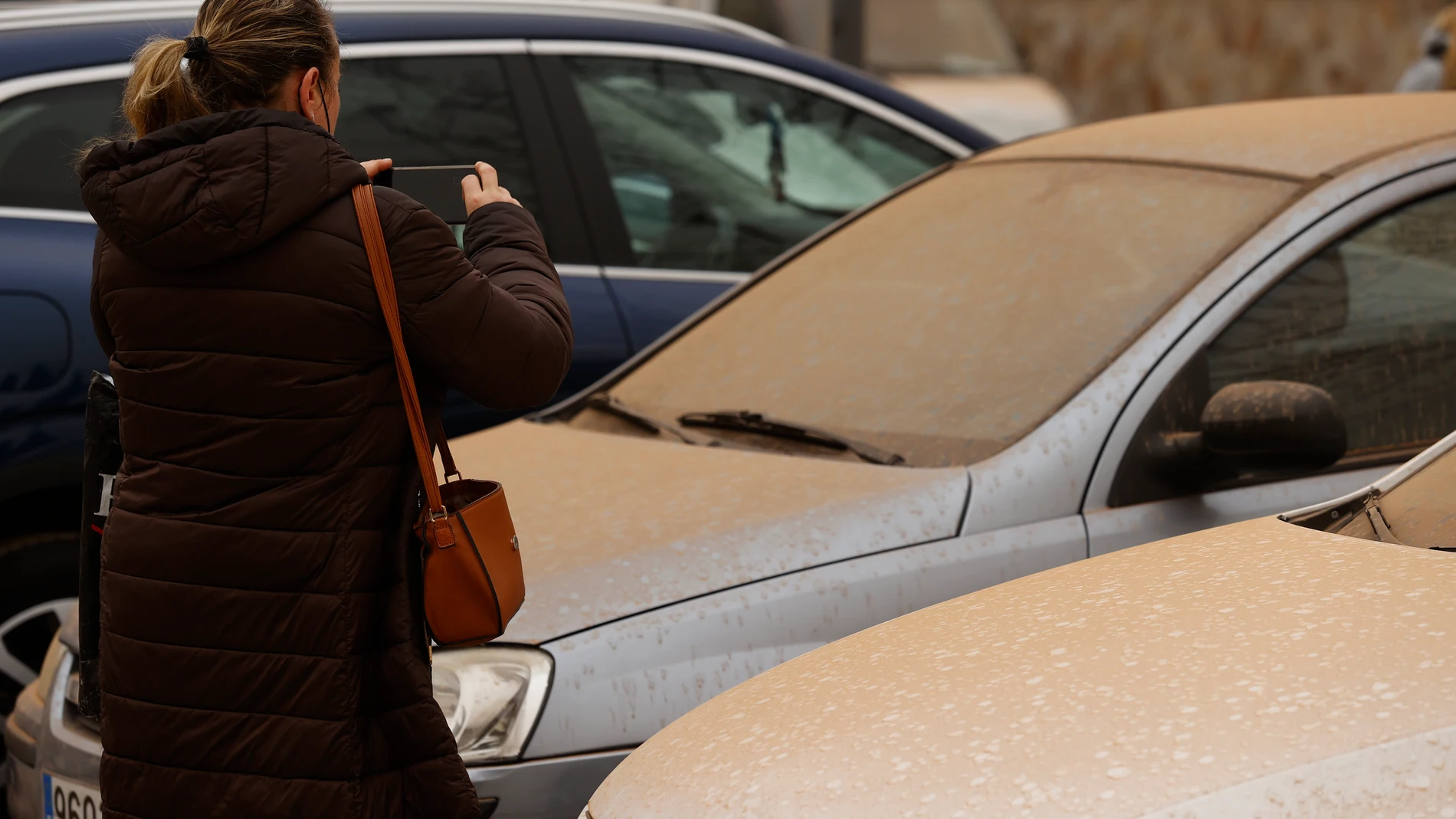 Una mujer hace una foto del polvo en suspensión que proviene del Sáhara que tras la lluvia acaecida en Madrid este martes ha teñido la ciudad de un color naranja. EFE/ Chema Moya