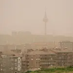 Una mujer observa la calima y la lluvia desde el mirador del Cerro del Tío Pío, Madrid