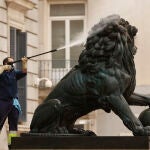 Un operario utiliza agua a presión para limpiar uno de los leones del Congreso, este martes | Fuente: EFE/ Chema Moya