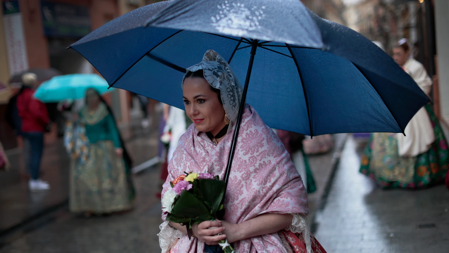 Una fallera se protege de la lluvia con un paraguas a falta de dos días y medio para que acaben las Fallas de 2022