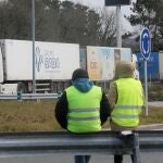 Dos miembros de un piquete observan los camiones estacionados en una rotonda de O Corgo (Lugo), durante el cuarto día de paros en el sector de los transportes, a 17 de marzo de 2022